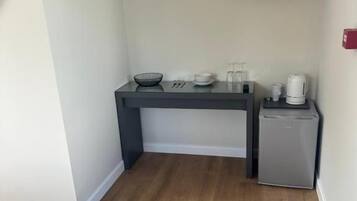 Una cocina compacta con una televisión de pantalla plana, un refrigerador pequeño y una cafetera sobre la encimera.
