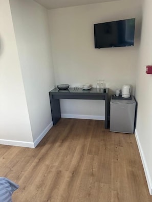 A compact kitchen with a flat-screen TV, a small refrigerator, and a coffee maker on the counter. - Cedarwood B&B (FELTON)