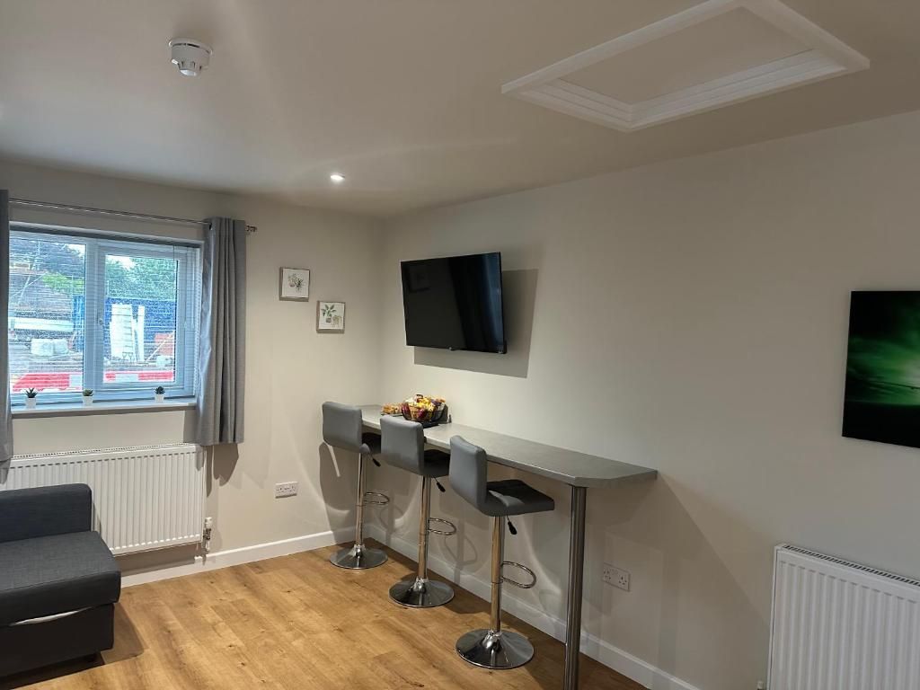 Una cocina moderna con comedor, un televisor montado en la pared y una ventana con cortinas.