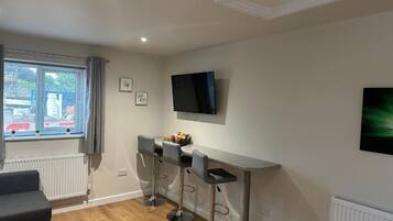 Una cocina moderna con comedor, un televisor montado en la pared y una ventana con cortinas.