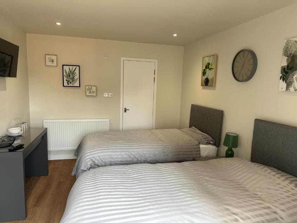 A bedroom with two beds, a bedside table, a lamp, and wall-mounted artwork.