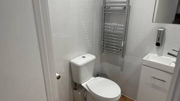 A compact bathroom with a white toilet, a chrome towel rack, and a white sink.