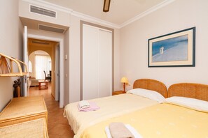 Ein Hotelzimmer mit einem Bett, einem Nachttisch mit Lampe, einem Bild an der Wand und Blick auf den Flur.