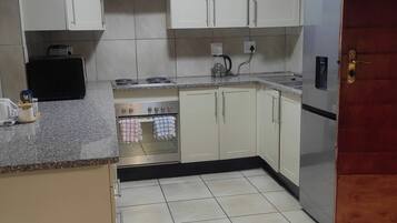 A kitchen with white cabinets, a stove, a sink, and a refrigerator.