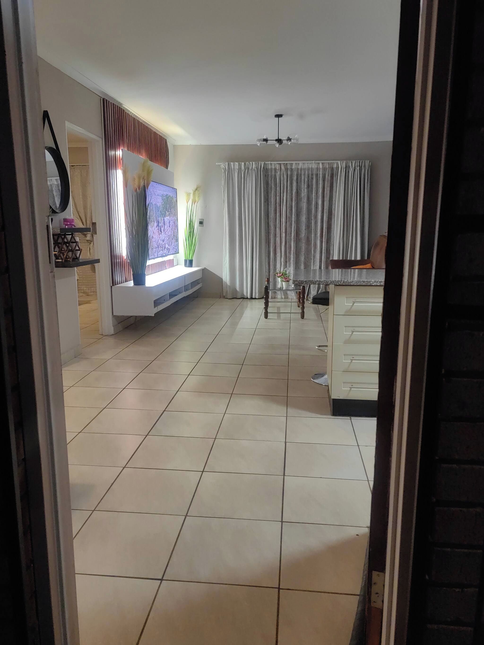 Amplia sala de estar con televisor de pantalla plana, ventilador de techo y comedor con mesa y sillas.