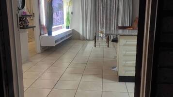 Amplia sala de estar con televisor de pantalla plana, ventilador de techo y comedor con mesa y sillas.