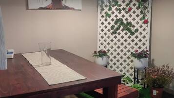Un comedor con una mesa de madera, un banco, una planta en maceta y una lámpara fijada a la pared.