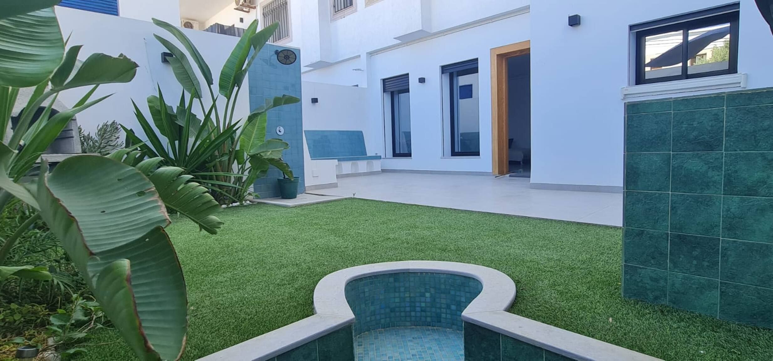 Un bâtiment moderne doté d’une piscine, d’un patio couvert et d’une pelouse bien entretenue.