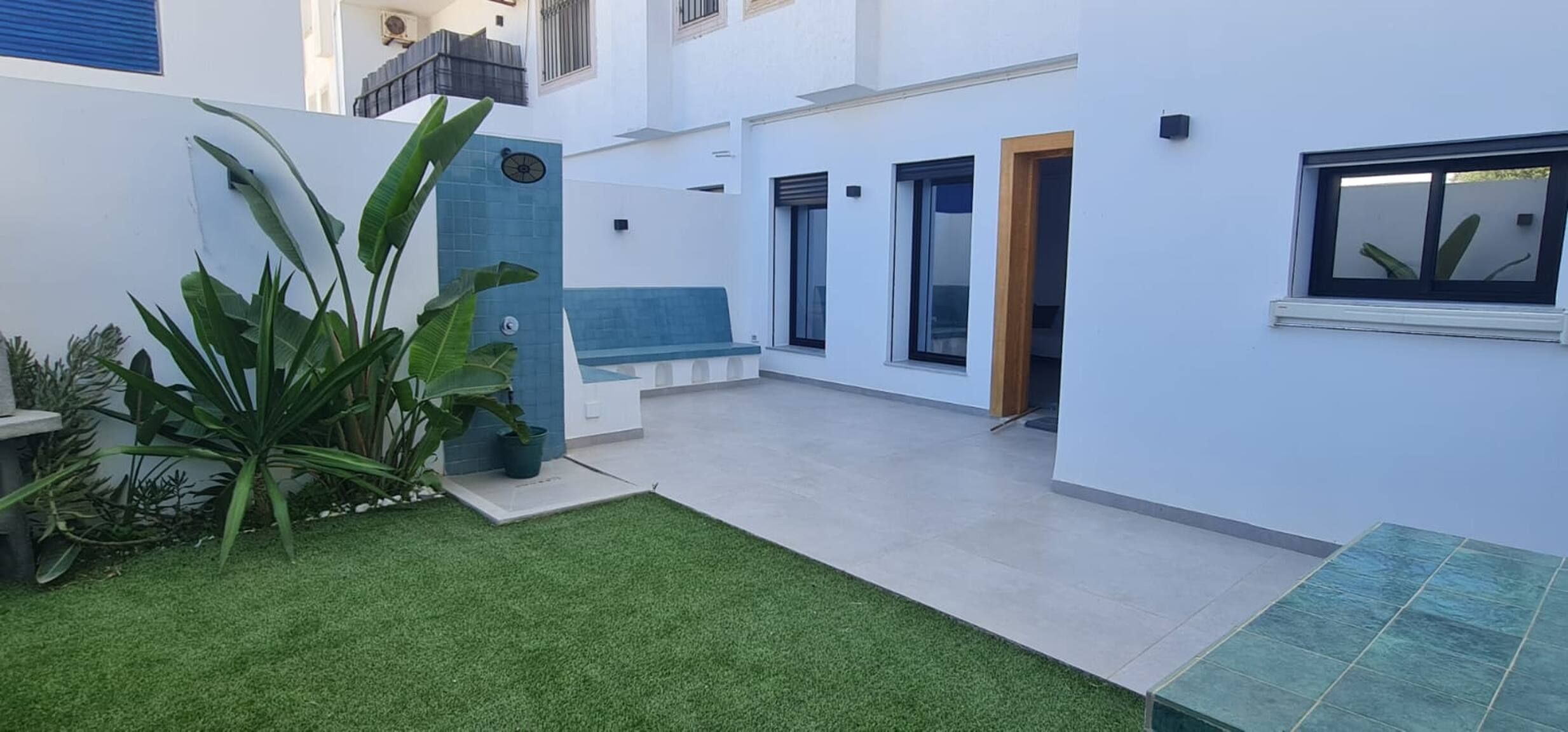 Un espace extérieur moderne doté d’une petite piscine, d’un coin salon et de plantes en pot.