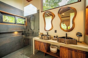 A modern bathroom with a glass shower enclosure, two wooden vanity sinks, and large mirrors. - Luxurious Beachfront Villa with Private Pool in Punta Uva (Punta Uva)