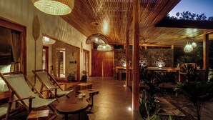 A modern interior with wooden furniture, a central dining area, and a stone wall. - Luxurious Beachfront Villa with Private Pool in Punta Uva (Punta Uva)