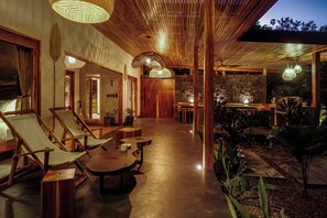 A modern interior with wooden furniture, a central dining area, and a stone wall. - Luxurious Beachfront Villa with Private Pool in Punta Uva (Punta Uva)