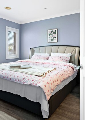 A bedroom with a bed, a window with blinds, a wall-mounted picture, and a door. - Stylish Taylors Hill Kingdom (Taylors Hill)