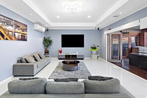A modern living room with a grey sofa, a coffee table, and a flat-screen TV mounted on the wall. - Stylish Taylors Hill Kingdom (Taylors Hill)