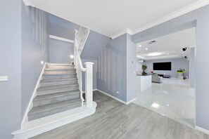 A modern interior with a staircase, a living area, and a kitchen. - Stylish Taylors Hill Kingdom (Taylors Hill)