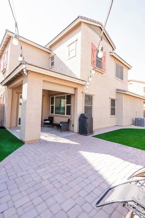 A two-story house with a covered patio area, outdoor seating, and a grill. - Casa Encanto  - EV Charger, Pool, AC, H20 Filter (Goodyear)