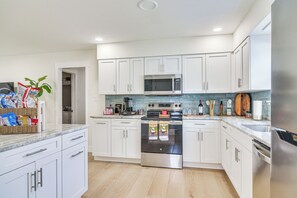 Eine moderne Küche mit weißen Schränken, einem Edelstahl-Kühlschrank, einer Mikrowelle und einem Backofen.