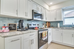 A modern kitchen with white cabinets, a built-in oven, a coffee machine, and a sign that reads 'WELCOME BRANDON PALM RETREAT'. - Fully Remodeled Brandon Escape w/ Fenced Yard! (Brandon)