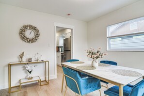 A modern dining area with a marble table, blue velvet chairs, and a decorative wall clock. - Fully Remodeled Brandon Escape w/ Fenced Yard! (Brandon)