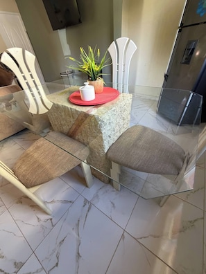A dining area with a marble-tiled floor, a glass table, and white chairs with cushioned seats. - Luxurious 5-Bedroom House with Private Pool in Cabrera (Cabrera)