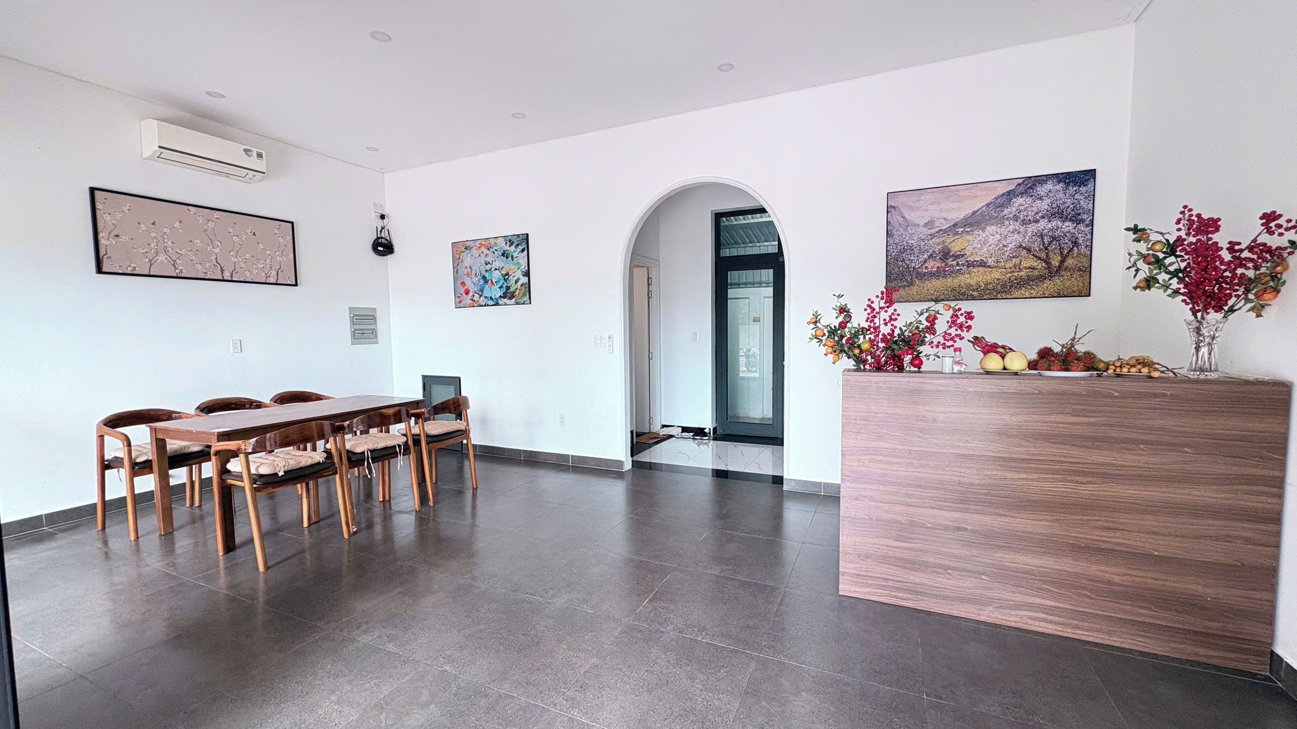 A spacious room with a wooden dining table and chairs, a reception desk, and artwork on the walls.