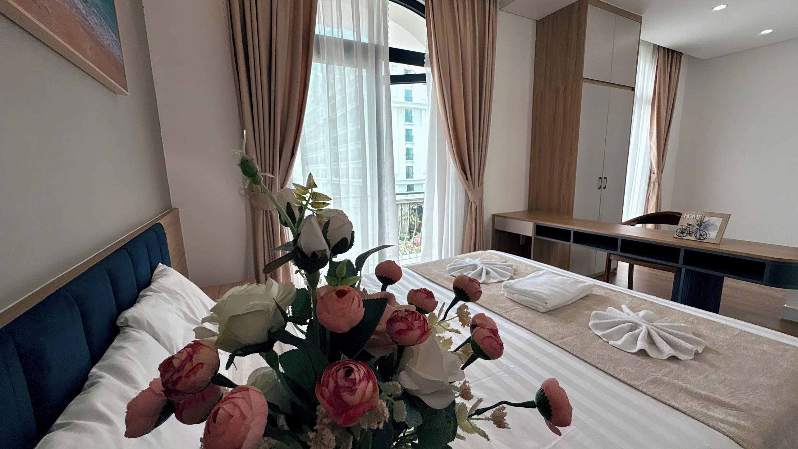 Ett hotellrum med en säng, ett sängbord, en spegel och ett fönster med gardiner.