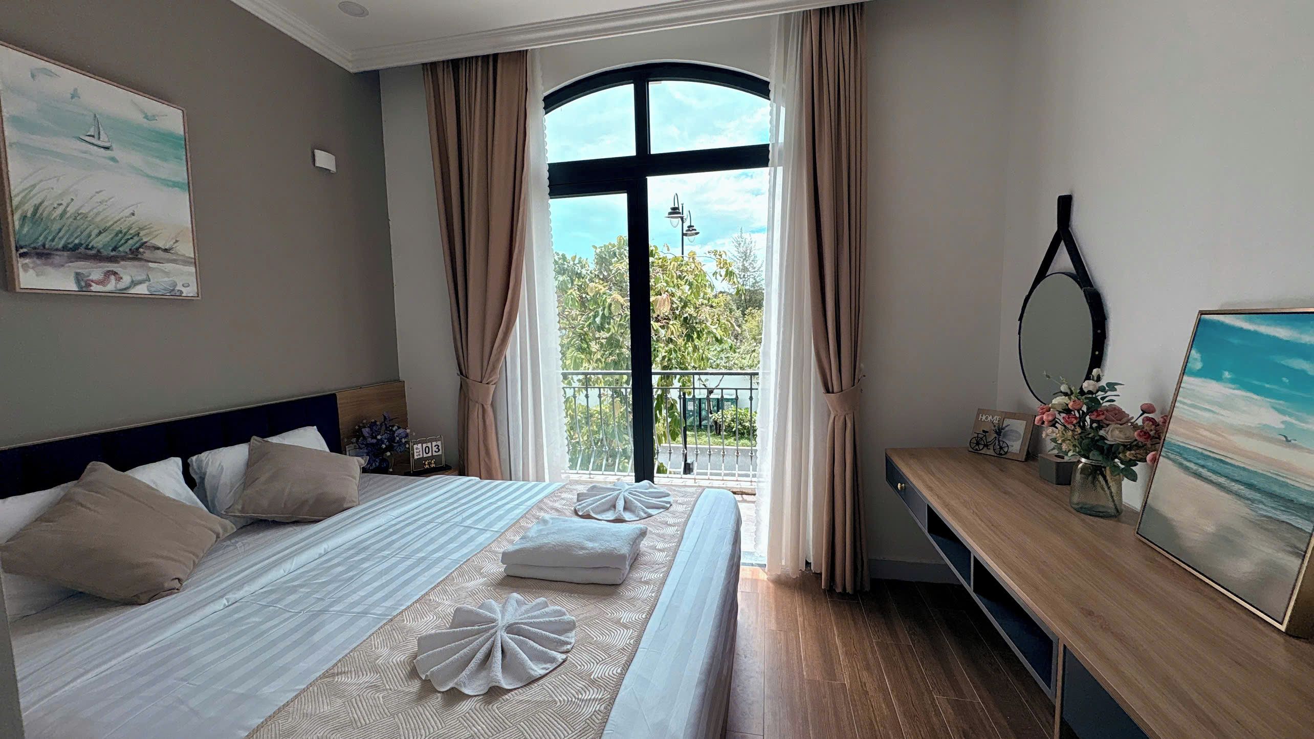 Une chambre d’hôtel avec un lit, une table de chevet en bois, un miroir et une vue sur l’extérieur.