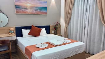 Une chambre d’hôtel avec un lit, une table de chevet, un ours en peluche, un tableau représentant une plage et un vase rempli de fleurs.