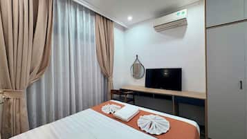 Une chambre d’hôtel équipée d’un lit, d’un bureau, d’une télévision et d’un climatiseur.