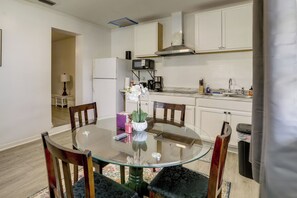 A modern kitchen with white cabinets, a stainless steel range hood, and a glass dining table with chairs. - 5 Mi to Ocean! Snowbird Haven in Lake Worth Beach (Lake Worth Beach)