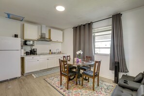A compact kitchen with white cabinets, a microwave, and a coffee maker. There is a dining table with chairs and a small potted orchid. - 5 Mi to Ocean! Snowbird Haven in Lake Worth Beach (Lake Worth Beach)