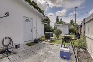 A residential backyard with a white garage, a small shed, a barbecue grill, and a portable gas stove. - 5 Mi to Ocean! Snowbird Haven in Lake Worth Beach (Lake Worth Beach)