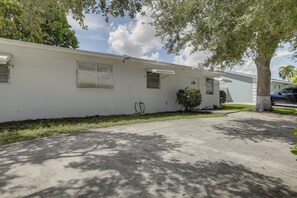 A single-story mobile home with a garage, a small front yard, and a tree providing shade. - 5 Mi to Ocean! Snowbird Haven in Lake Worth Beach (Lake Worth Beach)