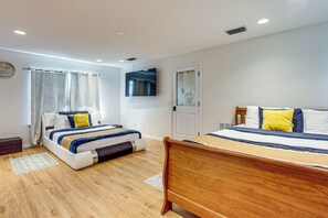 Ein Hotelzimmer mit zwei Betten, einem flachbildfernseher an der Wand und Holzboden.