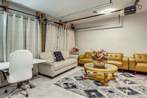 Una sala de estar con un escritorio blanco, dos sofás, una mesa de centro y un tapete estampado.