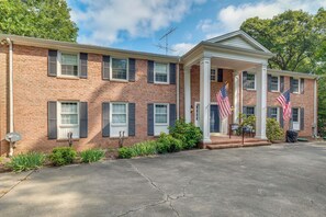 A two-story brick building with a covered porch and two American flags.
