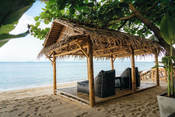 Shaded beachfront cabana with cozy lounge seating and ocean views