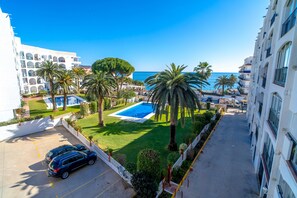 A residential area with a swimming pool, palm trees, and a view of the sea. - Studio in Nerja With Sea Views & Pool (Nerja)