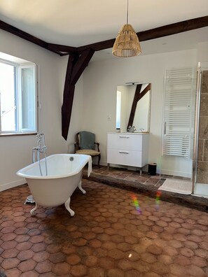 Ein Badezimmer mit freistehender Badewanne, einem Waschtisch mit Spiegel und einer Duschkabine.