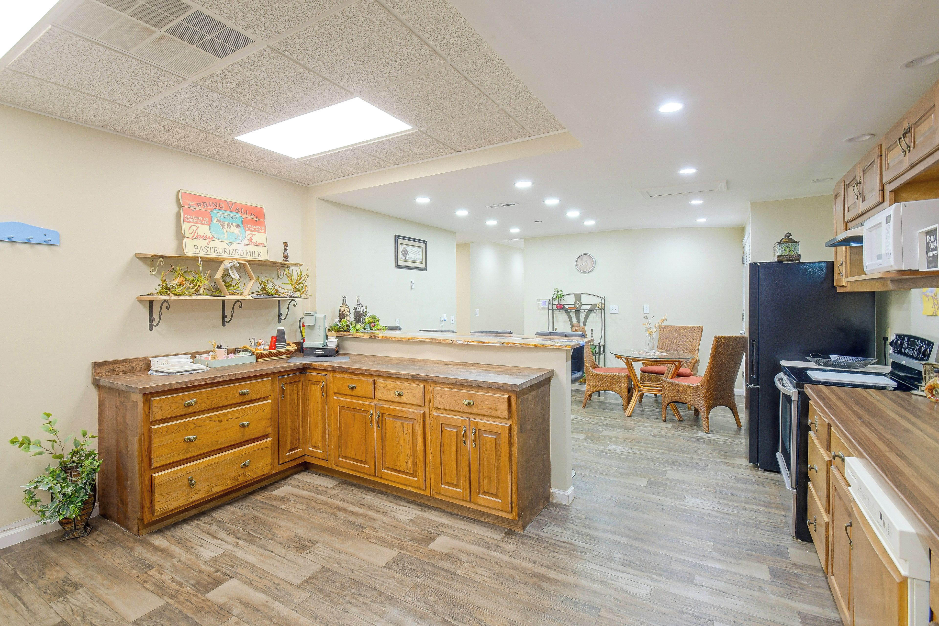 A kitchen with wooden cabinets, a central island, and a dining area with wicker chairs.