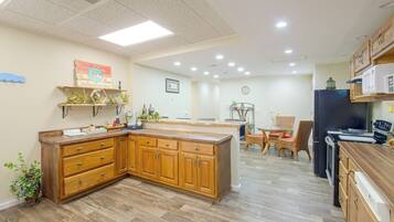 A kitchen with wooden cabinets, a central island, and a dining area with wicker chairs.