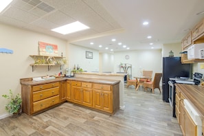 Una cocina con armarios de madera, una isla central y un comedor con sillas de mimbre.
