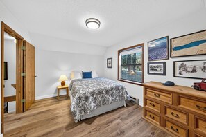 Ein Schlafzimmer mit einem Bett, einem Nachttisch, einer Kommode und Wandbildern.