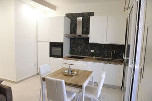 Eine moderne Küche mit weißen Schränken, einem Holztisch und einer schwarzen Spritzschutzwand.