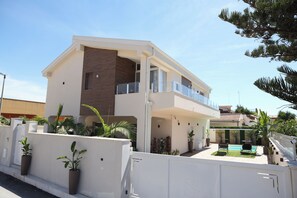 Una casa moderna de dos pisos con balcón, piscina y plantas en macetas.