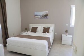Ein Hotelzimmer mit einem großen Bett, einem Nachttisch, einer Lampe und einem Bild an der Wand.