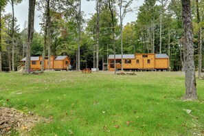 Une cabane dotée d’une terrasse et d’une table de pique-nique, située dans un cadre forestier.