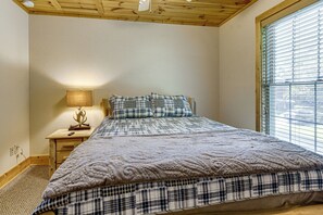 Un dormitorio con una cama, una mesita de noche, una lámpara y una ventana con persianas.
