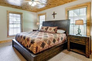 A bedroom with a large bed, wooden headboard, and a cross on the wall. - 5 Mi to Cataloochee Ski! Mtn-View Retreat w/ Deck (Maggie Valley)