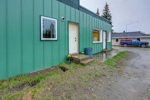 A green building with a white door, a small porch, and a blue truck parked outside. - Cozy Apartment Near UAF & Downtown Fairbanks! (Fairbanks)
